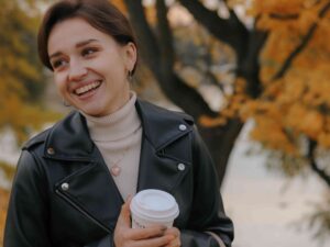 woman with beautiful smile outside holding coffee